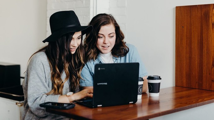 Friends using a laptop in a cafe and following ethical fashion influencers