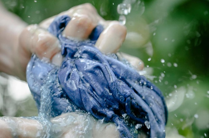 Hands squeezing wet clothes made with natural dyes in fashion